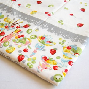 May include: White tablecloth with a gray scalloped border. The tablecloth features a repeating pattern of fruit-filled ice cream sundaes, cherries, strawberries, kiwi, and lemons.