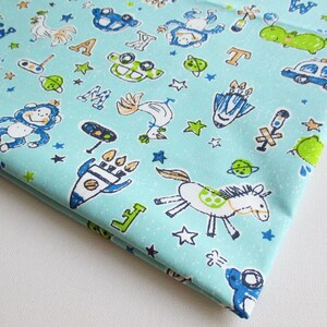 May include: A light blue fabric with a white background featuring a variety of colorful illustrations. The illustrations include a rocket, a horse, a monkey, a car, a rooster, a hippopotamus, and letters of the alphabet. The fabric is perfect for crafting projects.