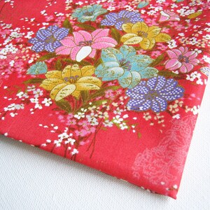 Może przedstawiać: Czerwony materiał z kwiatowym wzorem z różowymi, niebieskimi, żółtymi i białymi kwiatami. Materiał ma subtelny połysk i delikatną fakturę.