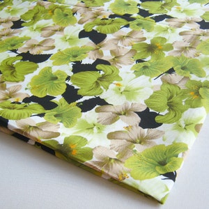 May include: White fabric with a repeating pattern of green and beige hibiscus flowers on a black background.