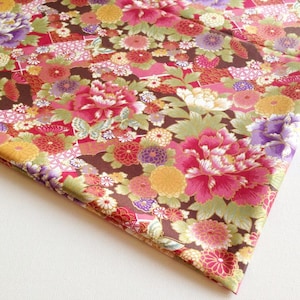 May include: A brown fabric with a floral pattern featuring pink, red, white, yellow, and purple flowers. The fabric has a gold metallic sheen.