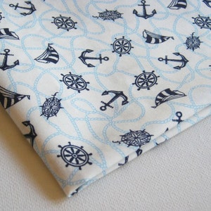 May include: White fabric with a nautical themed pattern. The pattern includes anchors, ships' wheels, compasses, and rope. The fabric is light blue and white.