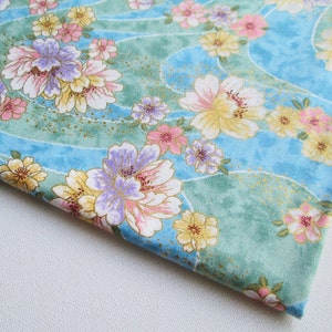 May include: Blue fabric with a floral pattern featuring pink, yellow, and purple flowers on a light blue background with a green and gold wave pattern.