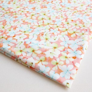 May include: A white fabric with a pink and orange floral pattern. The flowers are white with blue and green accents.