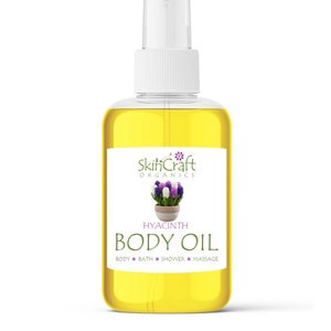 May include: A clear glass bottle of hyacinth body oil with a white spray top. The label reads "SkinCraft Organics" and features a graphic of hyacinth flowers. The words "HYACINTH BODY OIL" are printed below the graphic, with "BODY BATH SHOWER MASSAGE" below that.
