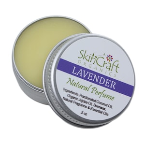 May include: A silver tin with a lavender-colored label that reads "SkinCraft Organics Lavender Natural Perfume". The label also lists the ingredients: Fractionated Coconut Oil, Organic Jojoba Oil, Beeswax, Natural Fragrance & Essential Oils. The tin contains a yellow balm and is labeled with "5 oz".