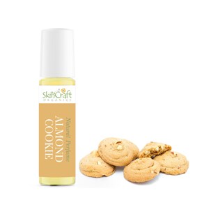 Puede incluir: Un peque&ntilde;o frasco de vidrio de perfume natural con aroma a almendra y galleta. El frasco tiene una tapa blanca de rodillo y una etiqueta amarilla con el texto "SkinCraft Organics" y "Natural Perfume Almond Cookie". Hay cinco galletas de almendras en el fondo.