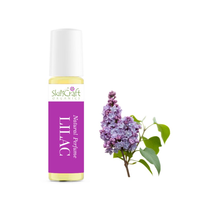 Puede incluir: Un peque&ntilde;o frasco de vidrio de perfume natural de lila con un tap&oacute;n blanco de rodillo. La botella est&aacute; etiquetada como "SkinCraft Organics Natural Perfume Lilac". A la derecha de la botella se muestra una rama de flores de lila con flores moradas.