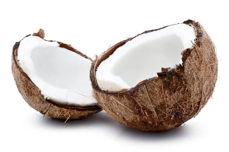May include: Two halves of a brown coconut with the white flesh visible inside. The coconuts are sitting on a white background.
