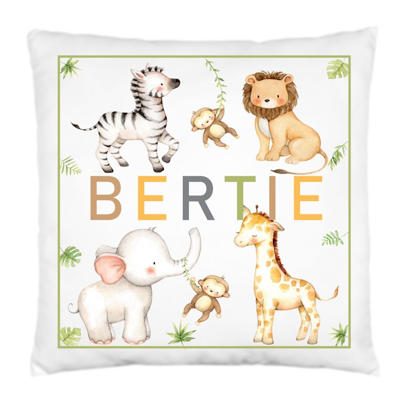 K&ouml;nnte beinhalten: Ein wei&szlig;es Kissen mit gr&uuml;nem Rand und einer Aquarell-Illustration eines Zebras, L&ouml;wen, Elefanten, Giraffen und Affen. Der Name "BERTIE" ist in braunen, gelben und grauen Buchstaben geschrieben.