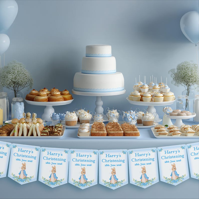 K&ouml;nnte beinhalten: Ein Tisch mit einer dreist&ouml;ckigen wei&szlig;en Torte, Cupcakes und Geb&auml;ck. Das Banner lautet "Harry's Christening". Die Desserts sind auf wei&szlig;en Servierplatten mit blauen Akzenten angerichtet.