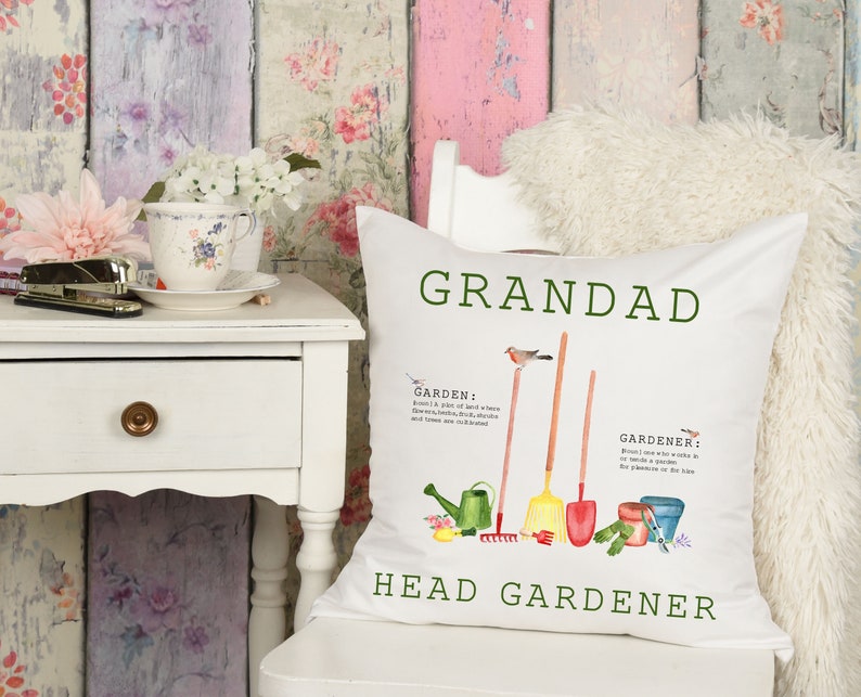 May include: White cushion with green text that reads "Grandad Head Gardener". The cushion features a watercolour illustration of gardening tools, a bird, and the words "Garden" and "Gardener" with definitions.