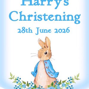 K&ouml;nnte beinhalten: Hellblaues Banner mit der Aufschrift "Harry's Christening 28th June 2026". Es zeigt eine Illustration eines Hasen in einem blauen Jackett, umgeben von blauen Blumen. Der Stil ist aquarellartig.
