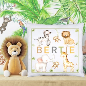 K&ouml;nnte beinhalten: Ein wei&szlig;es Kissen mit Dschungeltier-Motiv. Das Kissen zeigt ein Zebra, einen L&ouml;wen, einen Elefanten, eine Giraffe und Affen. Der Name "BERTIE" ist in braunen, gelben und grauen Buchstaben geschrieben.
