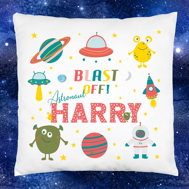 K&ouml;nnte beinhalten: Wei&szlig;er Kissenbezug mit Weltraumthema. Er zeigt eine Rakete, Planeten, Sterne, Au&szlig;erirdische und ein Raumschiff. Der Text lautet "Blast Off! Astronaut Harry".