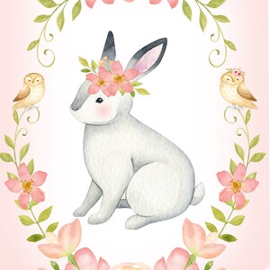 Op de afbeelding: Een aquarel-illustratie van een wit konijn met een roze bloemenkrans, omringd door roze bloemen en groene bladeren. Twee kleine bruine uilen zitten op takken aan weerszijden van het konijn.