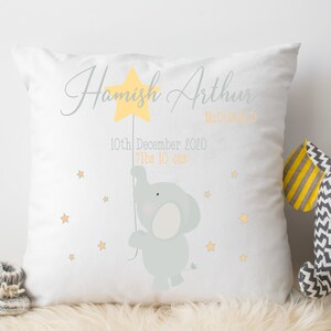 May include: A white pillow with a gray elephant holding a yellow star. The pillow is personalized with the name "Hamish Arthur" and the date "10th December 2020".