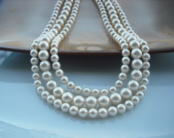 May include: A multi-strand pearl necklace with large, white pearls. The necklace is layered and has a classic, elegant look.