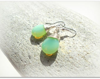 May include: A pair of silver earrings with green and yellow teardrop-shaped glass beads wrapped in silver wire.