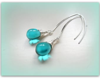 May include: A pair of silver dangle earrings with turquoise teardrop-shaped glass beads. The beads are wrapped in silver wire.