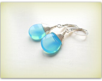 May include: A pair of silver wire wrapped earrings with light blue teardrop shaped stones.