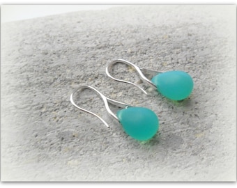 May include: A pair of silver dangle earrings with teardrop-shaped turquoise blue glass beads.