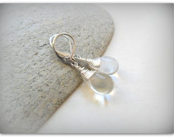 May include: Silver earrings with two clear teardrop-shaped stones wrapped in silver wire.