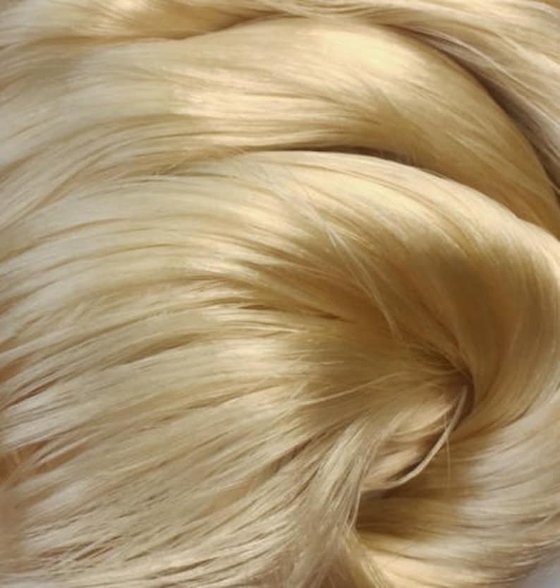May include: Close-up of a bundle of soft, light blonde silk fibers.