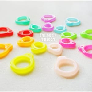 Op de afbeelding: Assortiment van kleurrijke plastic ringen, sommige doorschijnend, sommige ondoorzichtig, in verschillende tinten rood, oranje, geel, groen, blauw, roze en wit.