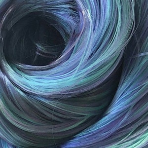 May include: Close-up of a blue and green hair extension. The hair is curled and twisted, creating a swirling pattern.