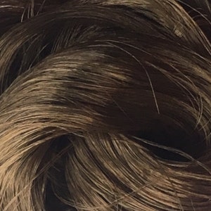 May include: Close-up of a brown hair extension. The hair is long and straight, with a slight wave. The hair is soft and silky.
