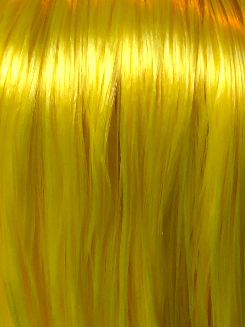 May include: Close-up of a bright yellow fiber, resembling a bundle of thin threads.