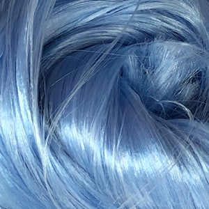 May include: Close-up of a bundle of light blue yarn. The yarn strands are tightly packed and have a silky, shiny texture. The fibers are twisted and layered, creating a dense, textured appearance. The colour is a soft, pastel blue.