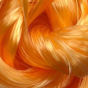May include: Close-up of a bundle of bright orange yarn. The yarn is soft and fluffy, with a slight sheen.