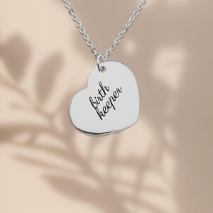 Pu&ograve; includere: Una collana con ciondolo a forma di cuore color argento con il testo birth keeper inciso in un carattere corsivo nero. Il ciondolo &egrave; appeso a una delicata catenina color argento, creando un gioiello semplice e raffinato.