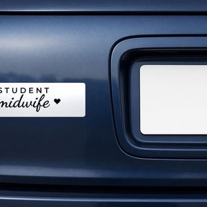 Pode incluir: Um autocolante retangular branco para para-choques com texto preto que diz STUDENT midwife seguido de um pequeno símbolo de coração preto. O autocolante está aplicado na bagageira azul escura de um veículo junto a uma matrícula.