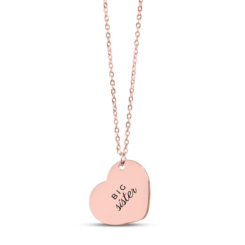 May include: A rose gold-toned necklace featuring a heart-shaped pendant. The pendant is engraved with the text BIG sister in a black, sans-serif font. The necklace consists of a delicate metal chain attached to the top of the heart charm.