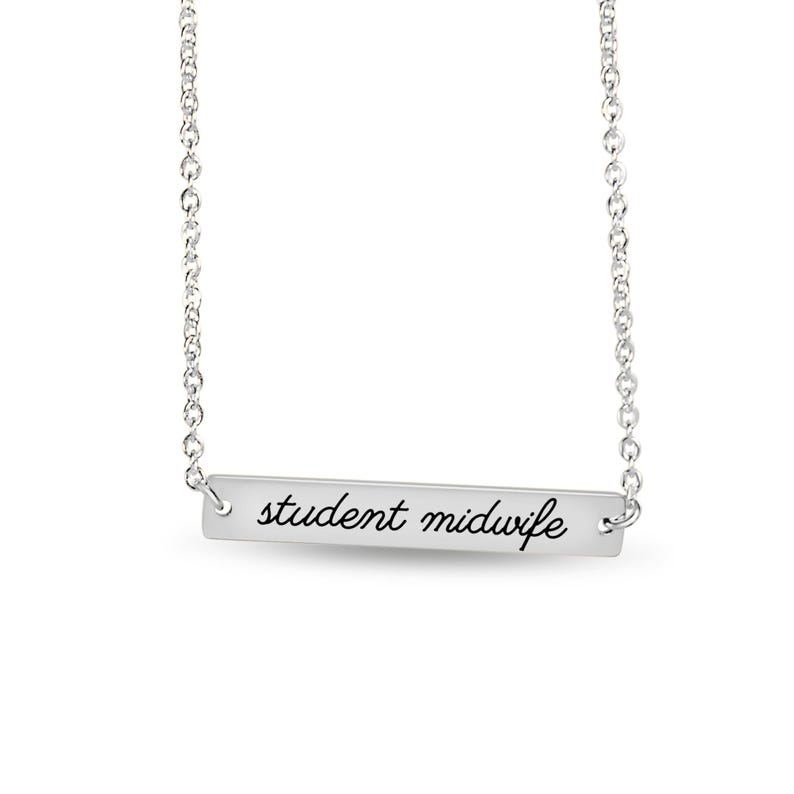 May include: A silver-toned bar necklace featuring a delicate chain and a horizontal rectangular pendant. The pendant is engraved with the text student midwife in a black cursive script font, centered on the polished metal surface.