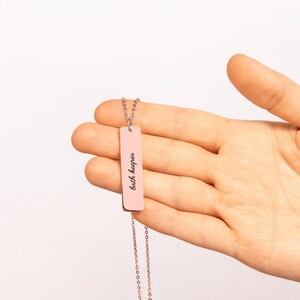 Op de afbeelding: Een ros&eacute;goudkleurige ketting met een verticale staafhanger met de gegraveerde tekst "birth keeper" in een cursief lettertype. De rechthoekige metalen bedel hangt aan een fijne bijpassende ketting met een gepolijste afwerking.