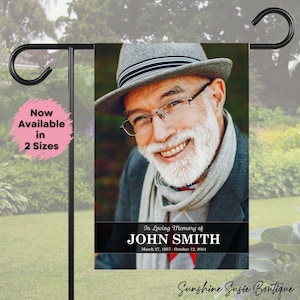May include: A garden flag featuring a smiling portrait of a man in a gray hat and glasses. The flag reads "In Loving Memory of John Smith" with dates. A pink circle with text indicates the flag is available in two sizes.