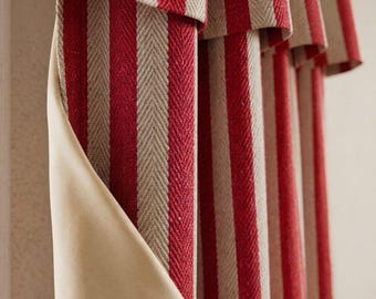 May include: A window curtain featuring a vertical red and beige striped pattern with a herringbone weave texture. The curtain has a pleated top section and a smooth, solid beige lining visible on the folded edge, creating a layered appearance.