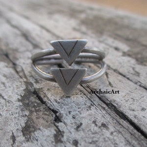 Può includere: Un anello d'argento con due disegni triangolari. I triangoli sono impilati uno sopra l'altro e hanno una superficie testurizzata.