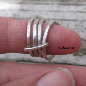 May include: A silver ring with a woven design. The ring is made of multiple strands of wire that are twisted together.