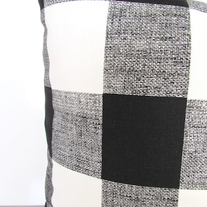 May include: Black and white checkered throw pillow with a subtle textured fabric.