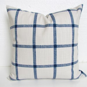 May include: A white pillow with a navy blue plaid pattern. The pillow is made of a soft, textured fabric.