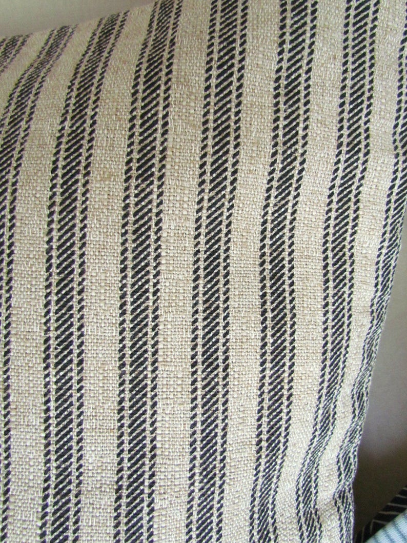 May include: Close-up of a beige and black striped fabric. The fabric has a woven texture and is made of natural fibers.
