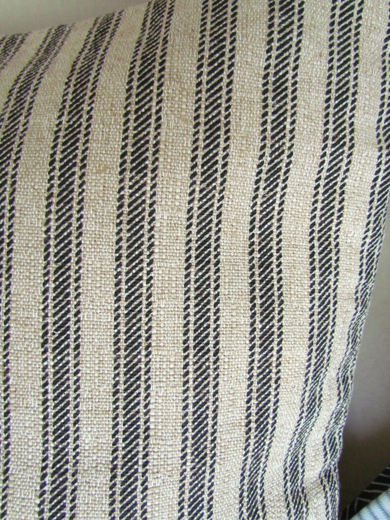 K&ouml;nnte beinhalten: Nahaufnahme eines beige-schwarz gestreiften Stoffes. Der Stoff hat eine gewebte Textur und besteht aus Naturfasern.