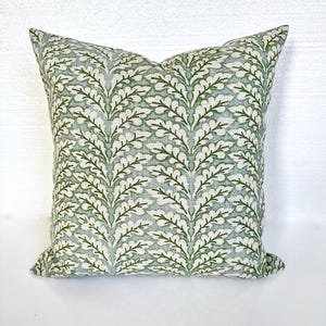 May include: A square throw pillow with a green and white leafy pattern. The pillow is made of a soft, textured fabric.