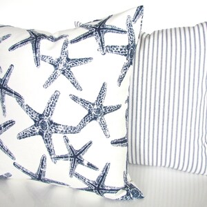 May include: Two decorative throw pillows. One pillow is white with a navy blue starfish pattern. The other pillow is white with navy blue stripes.