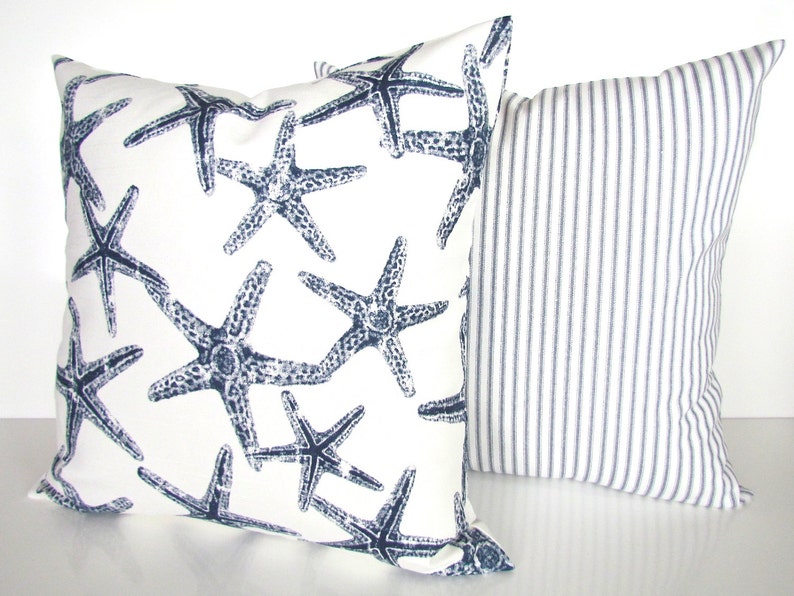 May include: Two decorative throw pillows. One pillow is white with a navy blue starfish pattern. The other pillow is white with navy blue stripes.
